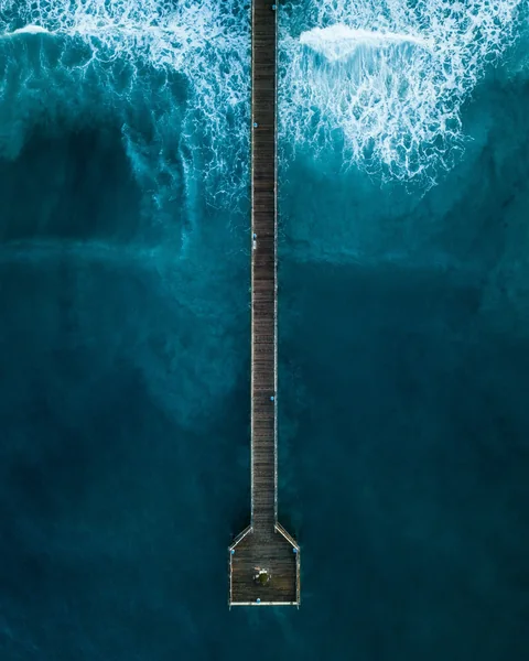 A pier extending into turquoise ocean waves